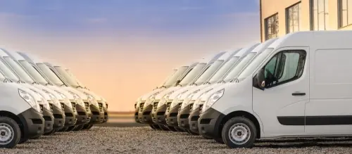 Sixteen delivery vans parked together that need commercial auto insurance