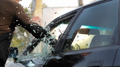 Man Breaking into a car by smashing the glass. I hope they have auto insurance